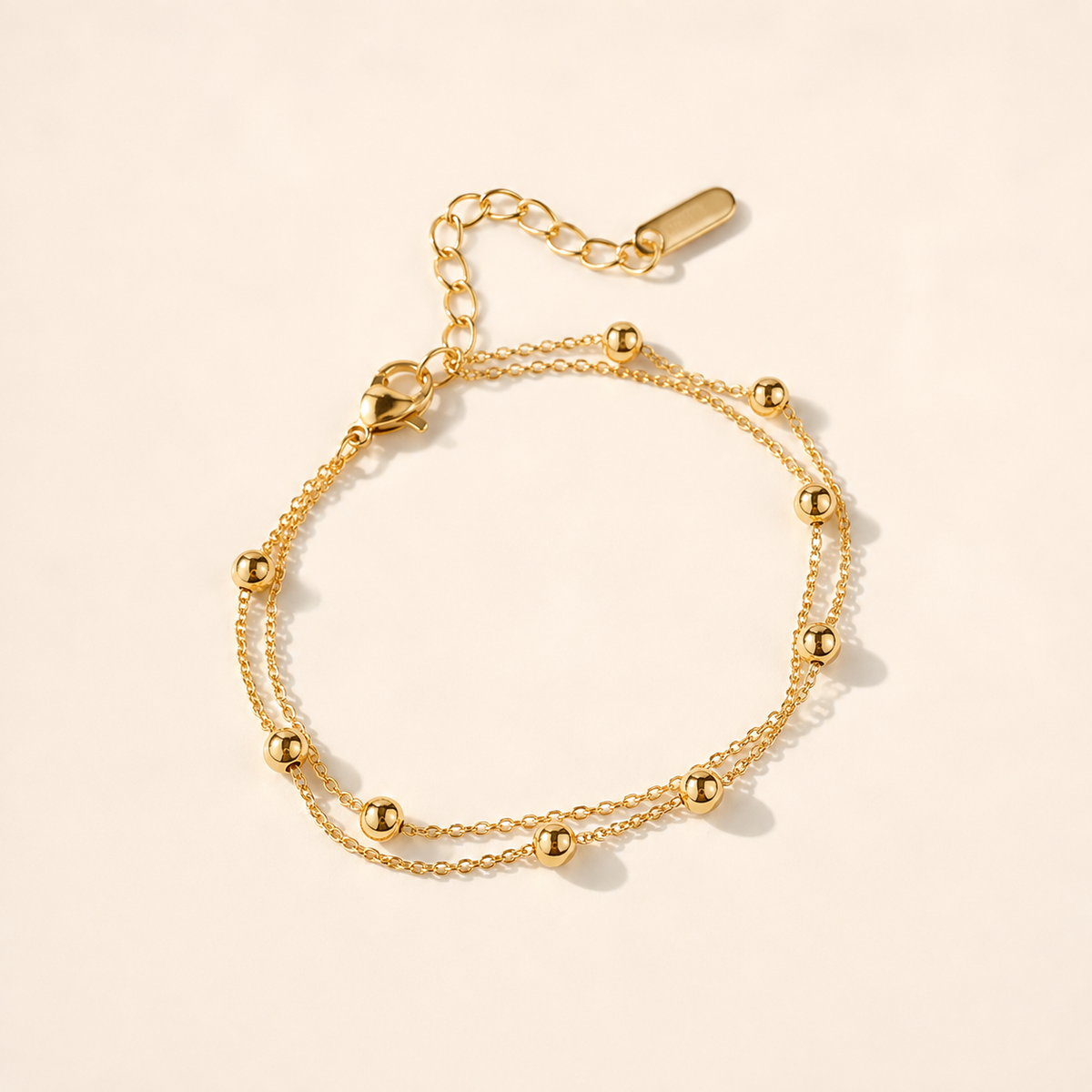 Double Layer Gold Bead anklet with two fine chains and polished gold beads on luxury ivory background