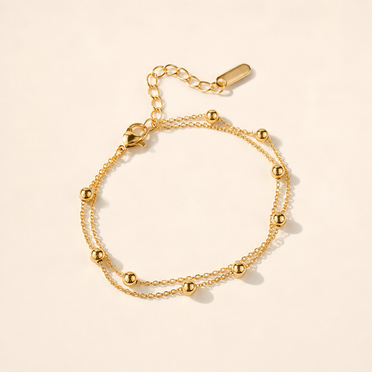 Double Layer Gold Bead anklet with two fine chains and polished gold beads on luxury ivory background