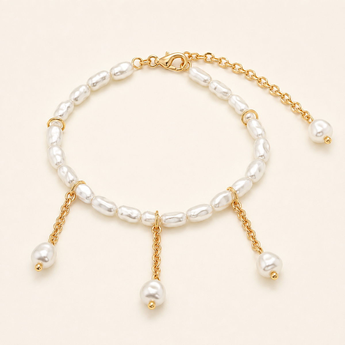 Faux pearl tassel pendant anklet with gold-tone chains on a warm ivory background