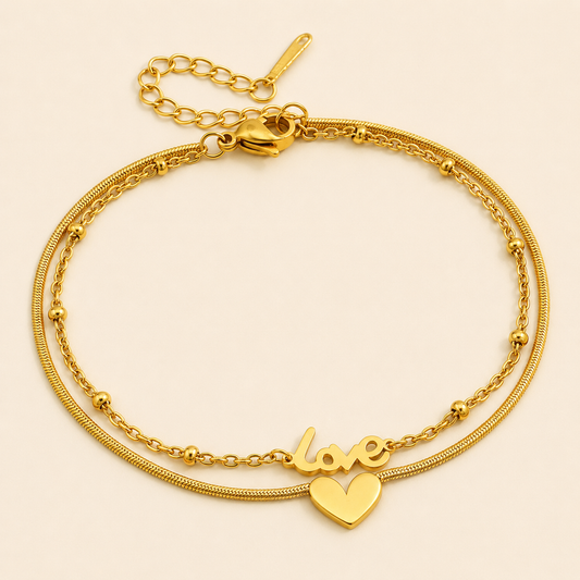 Double-layer gold anklet with Love script and heart pendant on warm ivory