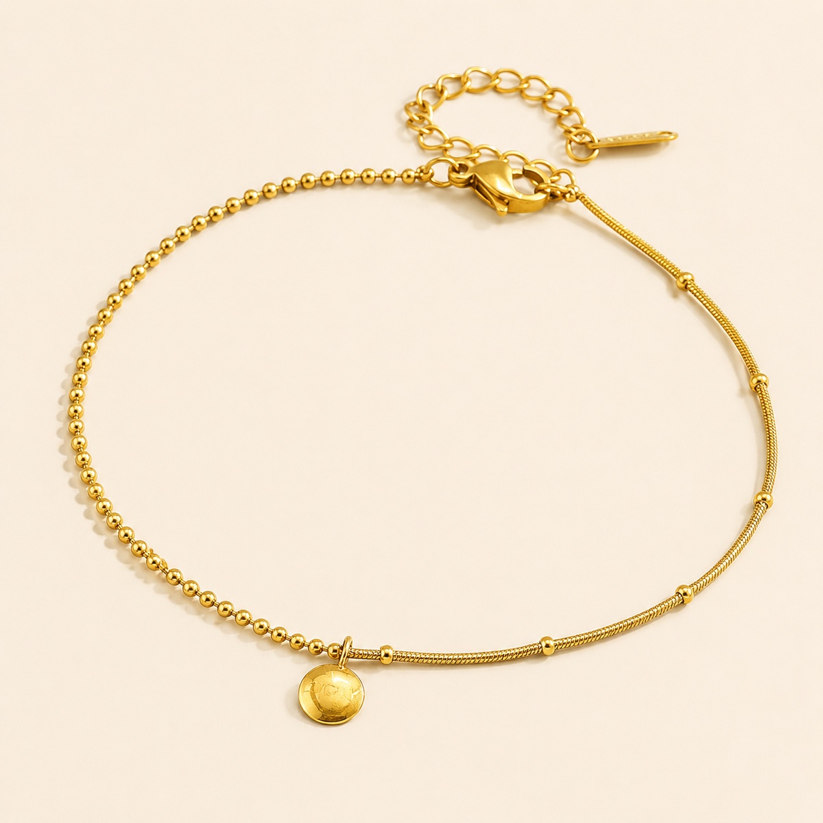 Asymmetric gold ball and snake chain anklet with round disc pendant on warm ivory