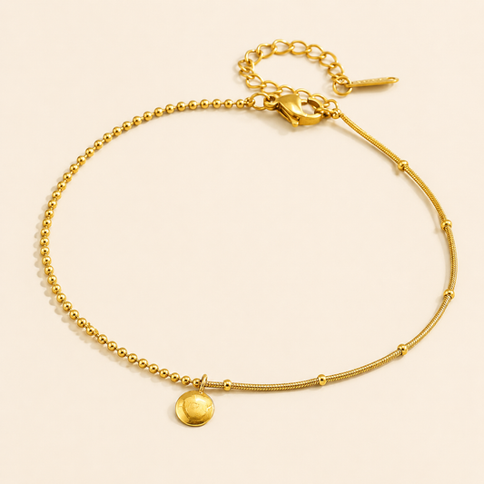 Asymmetric gold ball and snake chain anklet with round disc pendant on warm ivory