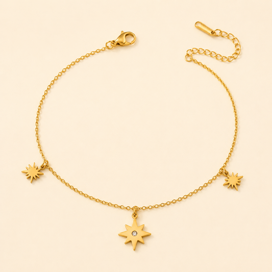 Gold anklet with three sunburst star charms and centre crystal on warm ivory